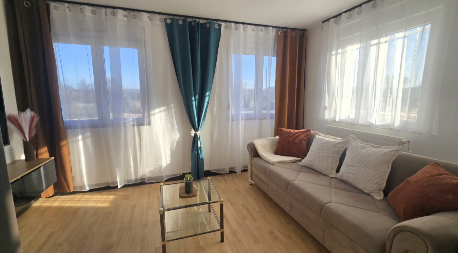 Salon lumineux de l’Appartement 1 avec canapé et grandes fenêtres